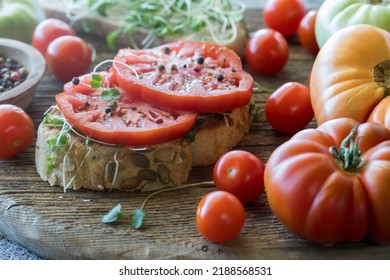 Pumpkin Seed Bread Topped With Micro Green Sprouts And Heirloom Tomatoes.