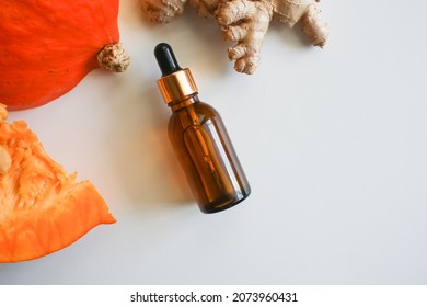 Pumpkin Seeds Oil Bottle, Pumpkins And Ginger Root. Selective Focus. Creative Flat Lay Of Glass Bottle With Organic Natural Pumpkin Seed Oil Extract Cosmetics For Skin And Hair Care.Minimal Beauty Spa