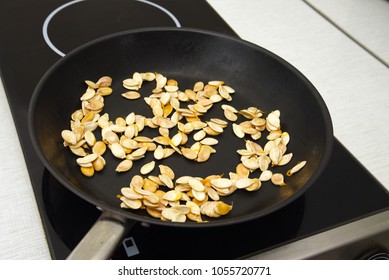 pumpkin seeds are roasted in a black pan, cooking theme, selected focus, narrow depth of field