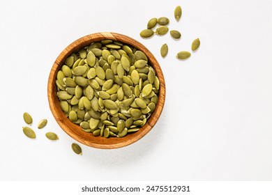 Pumpkin seeds in a wooden bowl, view from the top