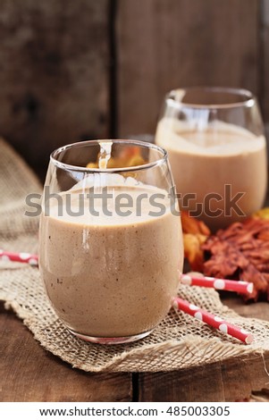 Pumpkin smoothies against a rustic background. Shallow depth of field with selective focus on dessert in foreground.