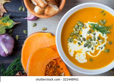 Pumpkin soup among autumn leaves on a wooden table 