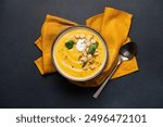 Pumpkin soup with cream and bread croutons in bowl on black background. Seasonal autumn dish on the table top view