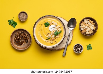 Pumpkin soup with cream and bread croutons in bowl on a yellow background. Seasonal autumn dish on the table top view - Powered by Shutterstock