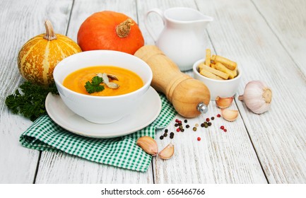 Pumpkin soup with fresh pumpkins on a old wooden table