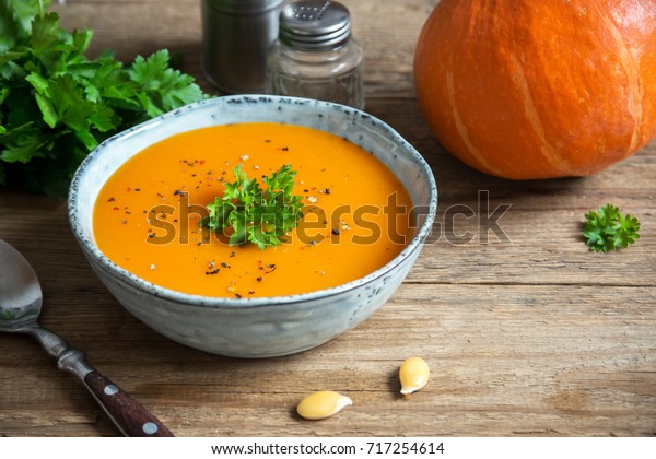Pumpkin soup and\
organic pumpkins on rustic wooden table. Seasonal autumn food -\
Spicy pumpkin ans carrot\
soup.