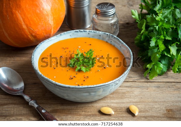 Pumpkin soup and\
organic pumpkins on rustic wooden table. Seasonal autumn food -\
Spicy pumpkin ans carrot\
soup.