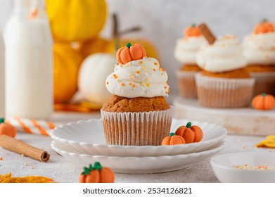 Pumpkin spice cupcakes decorated butter cream frosting, sugar sprinkles and mini sweet pumpkins on top. Thanksgiving or Halloween dessert - Powered by Shutterstock