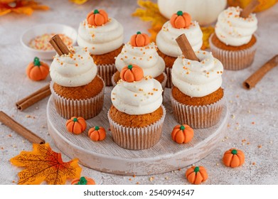 Pumpkin spice cupcakes decorated butter cream frosting, sugar sprinkles and mini sweet pumpkins on top. Thanksgiving or Halloween dessert - Powered by Shutterstock