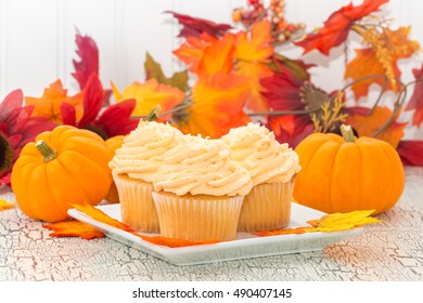 Pumpkin Spice Cupcakes In Front Of Colorful Fall Foliage.