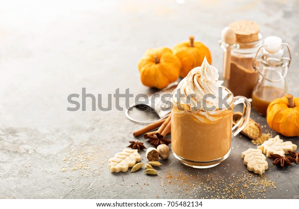 Pumpkin spice latte in a glass mug with cinnamon,\
nutmeg and cookies