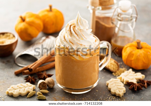 Pumpkin spice latte in a glass mug with cinnamon,\
nutmeg and cookies