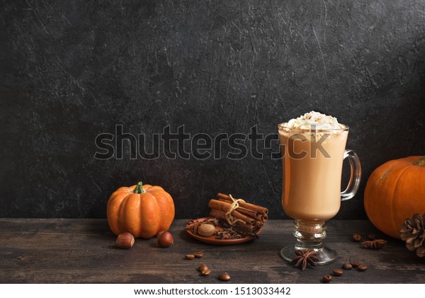 Pumpkin Spice Latte on black wooden background,\
copy space. Seasonal autumnal coffee drink with spices and organic\
pumpkins.