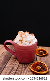 Pumpkin Spice Latter With Marshmallows And Cinnamon On Wooden And Black Background. Orange Spice Nearby. Food Background. Coffee Drink. Pink Mug. 