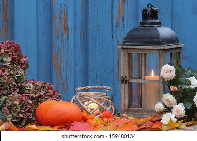 Pumpkin, storm lamp and lantern with white roses