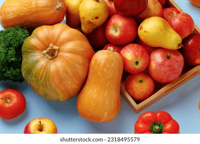 Pumpkins, apples and bell pepper composition on blue background