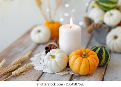 Pumpkins And Candle With Fairy Lights Around On A Wooden Table. Autumn Season Image, Cozy Home Atmosphere. Close Up