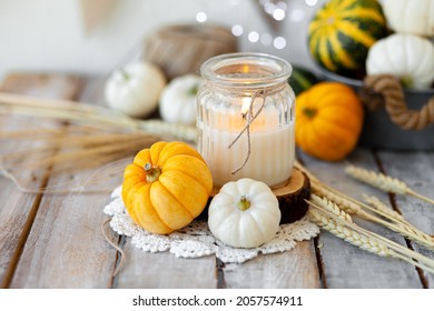 Pumpkins And Candle With Fairy Lights Around On A Wooden Table. Zero Waste Thanksgiving Dinner Table Decor. Autumn Season Image, Cozy Home Atmosphere. Close Up