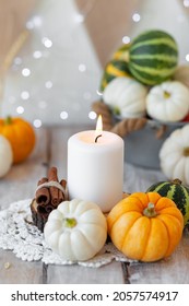 Pumpkins And Candle With Fairy Lights Around On A Wooden Table. Zero Waste Thanksgiving Dinner Table Decor. Autumn Season Image, Cozy Home Atmosphere. Close Up