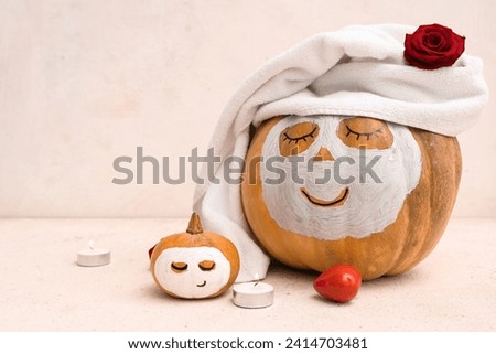 Pumpkins with drawn faces, candle, heart, rose and clay masks on light background