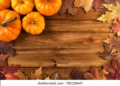 Pumpkins with fall leaves over wooden background. Top view.