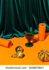 Pumpkins, green glass and orange cans against plush velvet curtain background. Creative Halloween and Thanksgiving table concept. Contemporary fall still life idea. - Shutterstock ID 2058870827