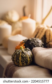 Pumpkins Next To The Window With Candles, Book And Warm Blanket. Cozy Home Atmosphere In Sunny Autumn Day. Cozy Fall Composition.