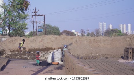 Puna / India - Mar 15, 2019: An Unidentified Child Labor Boy Working With His Father In A Brick Factory. Labors Working In Front Of High Society Buildings. Creative Concept Of Poverty Photography.