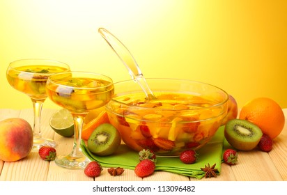 Punch In Bowl And Glasses With Fruits, On Wooden Table, On Yellow Background