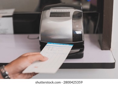 Punch card time clock machine processing attendance card in office setting, recording work hours and supporting workforce tracking and payroll accuracy.