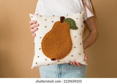 Punch needle embroidery pillow diy. Close-up of woman hands holding pillow. Product is made according to the technique pushing woolen threads on foundation fabric with needle with wood handle - Shutterstock ID 2129659253