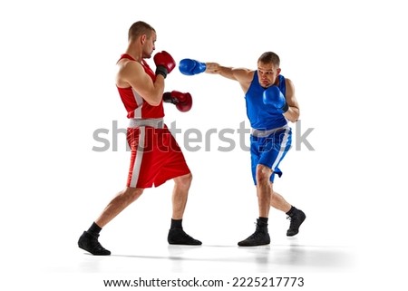 Punch. Two twins brothers, professional boxers in blue and red sportswear boxing isolated on white background. Concept of sport, competition, training, energy. Copy space for ad, text