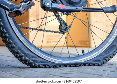 A punctured bicycle tire in selective focus against a background yellow sunlit wall in blur. - Powered by Shutterstock