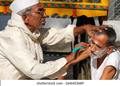 Pune, India - January 26 2020: A Road Side Barber Shaving A Man's Beard Outdoors At Pune India.