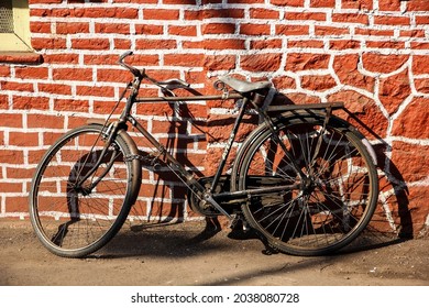 Pune, Maharashtra, India - August 2014: A Bicycle Parked Next To The Red Stone Brick Pattern Wall Of An Old Building In The City Of Pune.