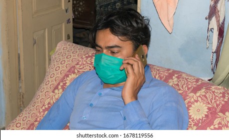 Punjab,Pakistan-March 20,2020:A Man With A Phone On Bed Wearing Face Mask For The Protection Of  Corona Virus (covid-19),air Pollution And Pollen Allergy.side View