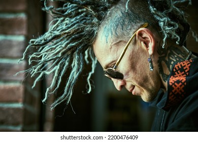 Punk culture. Profile portrait of a  mature brutal man with ethnic tattoos on his head and neck and with punk-style Mohawk dreadlocks.