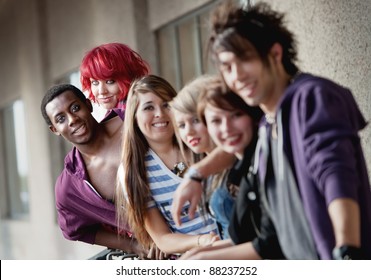 Punk Rock Looking Teens Smile At The Camera As The Camera Focuses On The Back Two Individuals.