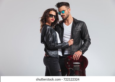 Punk Woman Holding Her Man By Jacket And Looks At The Camera, Rock And Roll Couple On Grey Studio Background