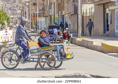 PUNO, PERU, MAY 5, 2014: Pedicab transports local woman  in city center