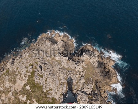 Punta nariga lighthouse casting a shadow over rocky coast and ocean waves