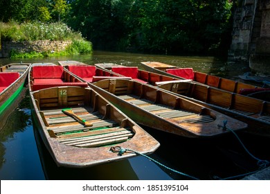 Punting boats by Magdalen Bridge Boathouse on river Cherwell in Oxford, many boats docked together in rows. Bright and colorfull group of long boats on sunny day.