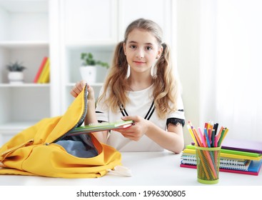 Pupil Child Put Books And Notes Into Backpack. School Supplies.Back To School Concept. School Girl Prepare Staff For Education. Kid Prepare For Studies. 