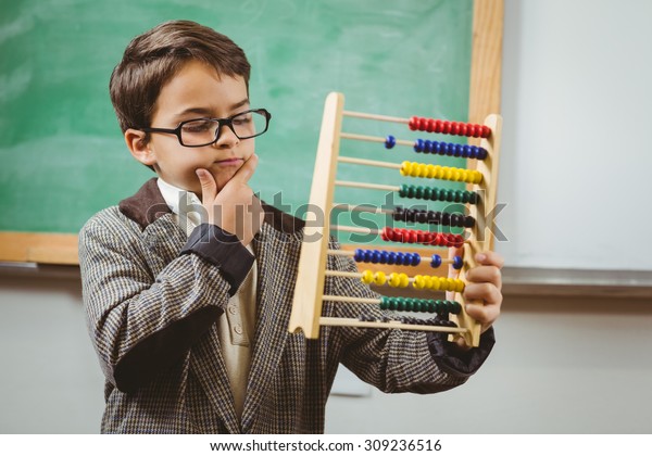 Pupil\
dressed up as teacher holding abacus in a\
classroom