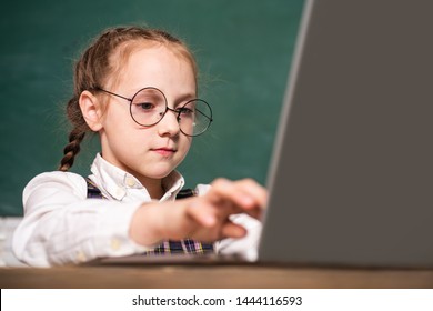 Pupil Girl Working On A Laptop. Cute Little Preschool Kid Boy Study In A Classroom. Educational Process. Elementary School And Education