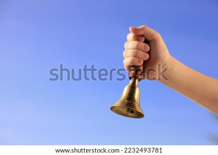 Pupil with school bell against beautiful sky, closeup. Space for text