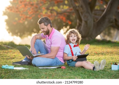 Pupil With Teacher Learning Outdoor By Studying Online And Working On Tablet In Park. Portrait Of Happy Family Father And His Son Using Laptop Outside.