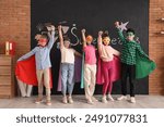 Pupils dressed as superheroes near blackboard in classroom