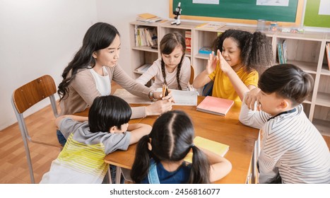 Pupils group study with teacher in classroom at elementary school. Students group study in primary school. Children learn activities in classroom. Education knowledge successful teamwork banner - Powered by Shutterstock