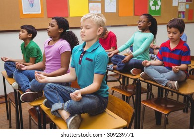 Pupils meditating on classroom desks at the elementary school - Powered by Shutterstock